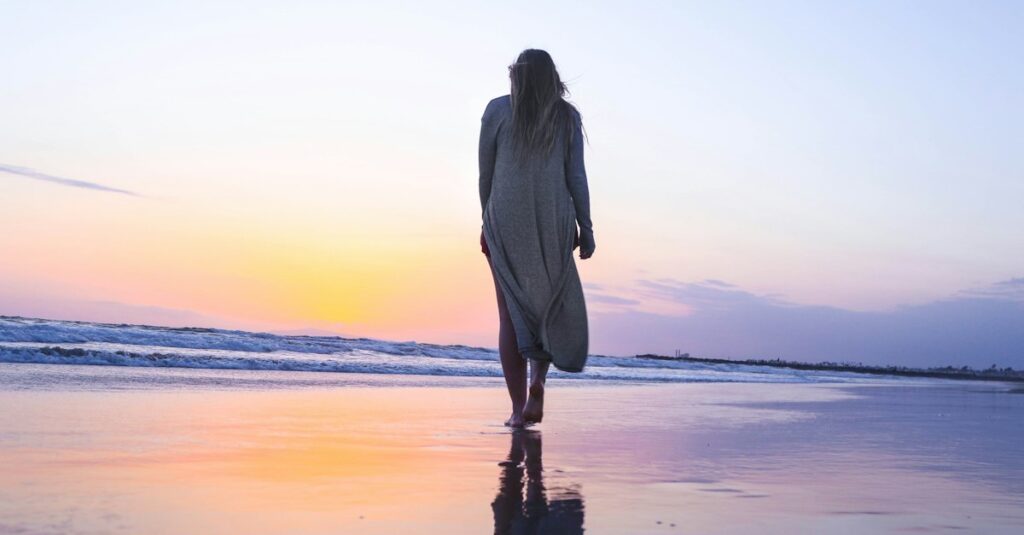 Woman walking calmly along a beach at sunset, representing nervous system regulation for perimenopause anxiety