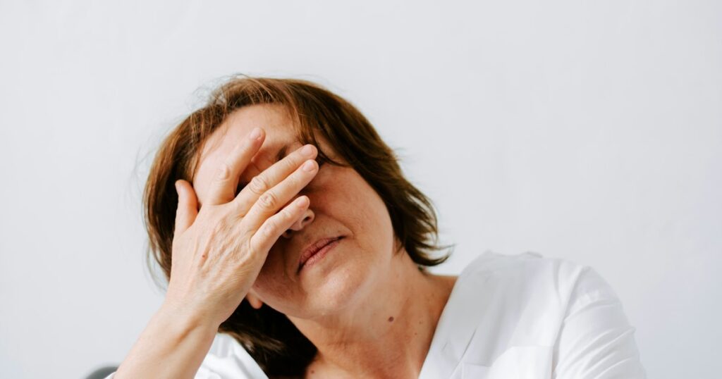 Midlife woman in her 40s covering her eyes with her hand, showing the overwhelm of a perimenopause mood swing
