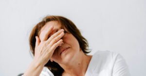 Midlife woman in her 40s covering her eyes with her hand, showing the overwhelm of a perimenopause mood swing